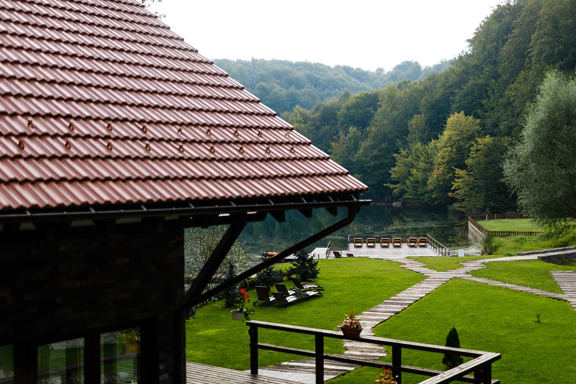 Vedere spre lac și gazon de sub acoperișul terasei