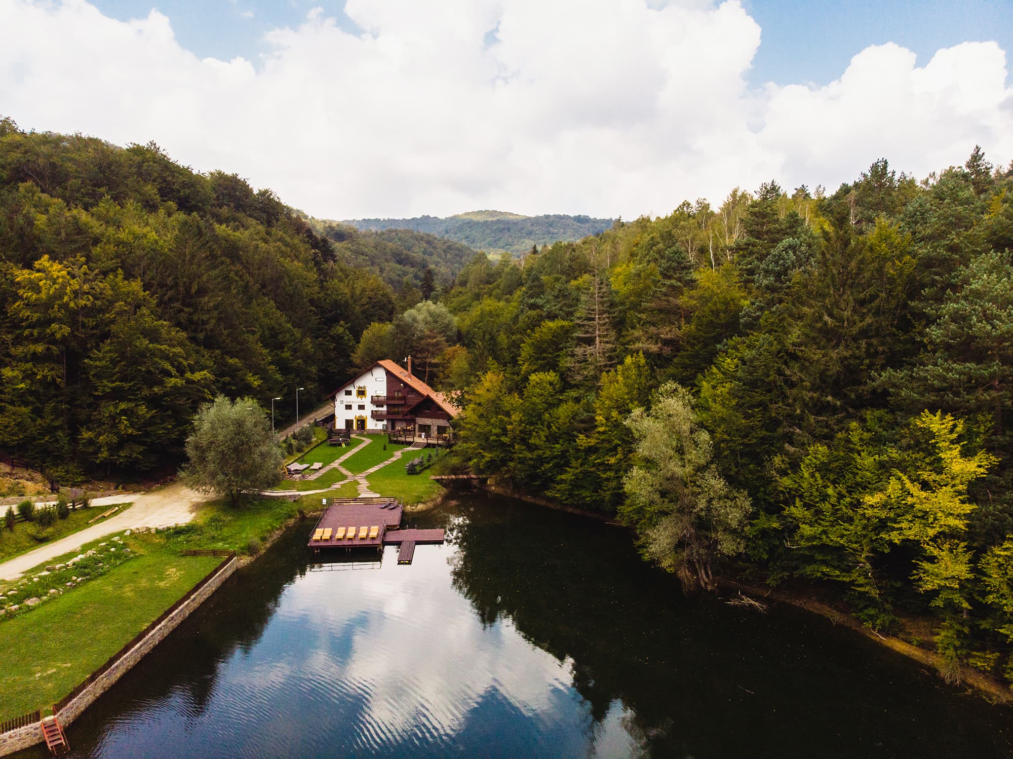 Vedere aeriană cu pensiunea Gasthaus Grindeshti pe malul golfului Grindeshti al lacului Gozna, înconjurată de pădure
