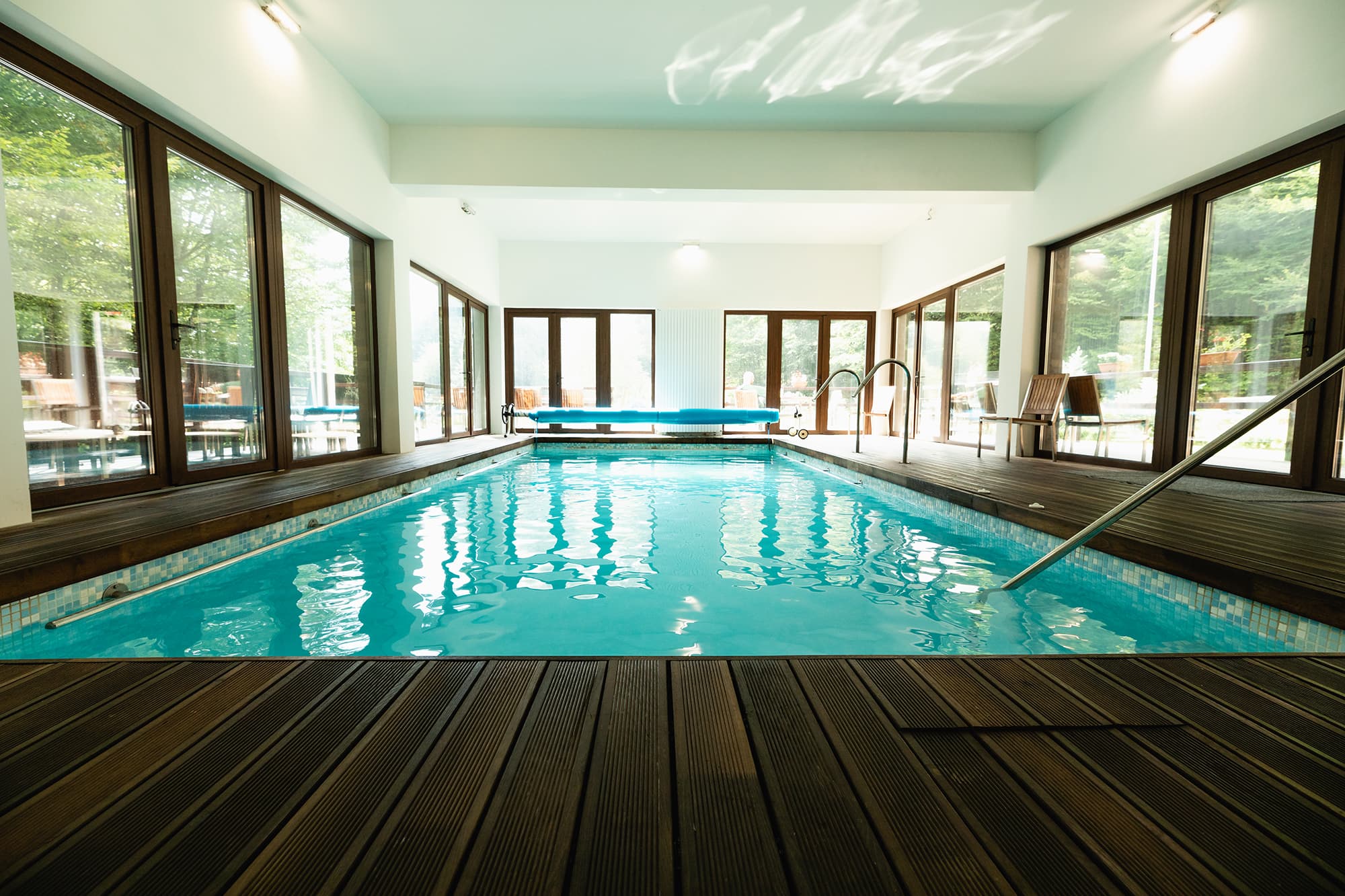 Piscina interioară încălzită a pensiunii, cu ferestre mari spre pădure