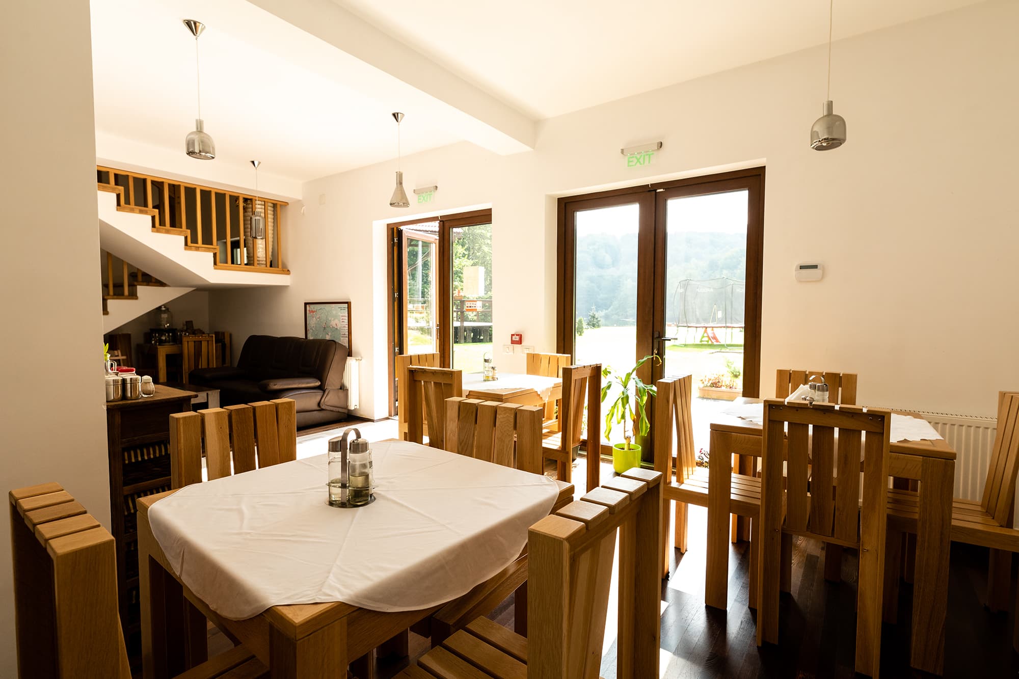 Interiorul luminos al restaurantului pensiunii, cu fețe de masă albe